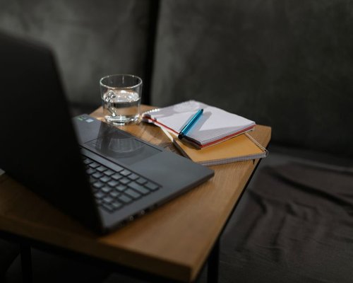 Water and notebook on a wooden work desk